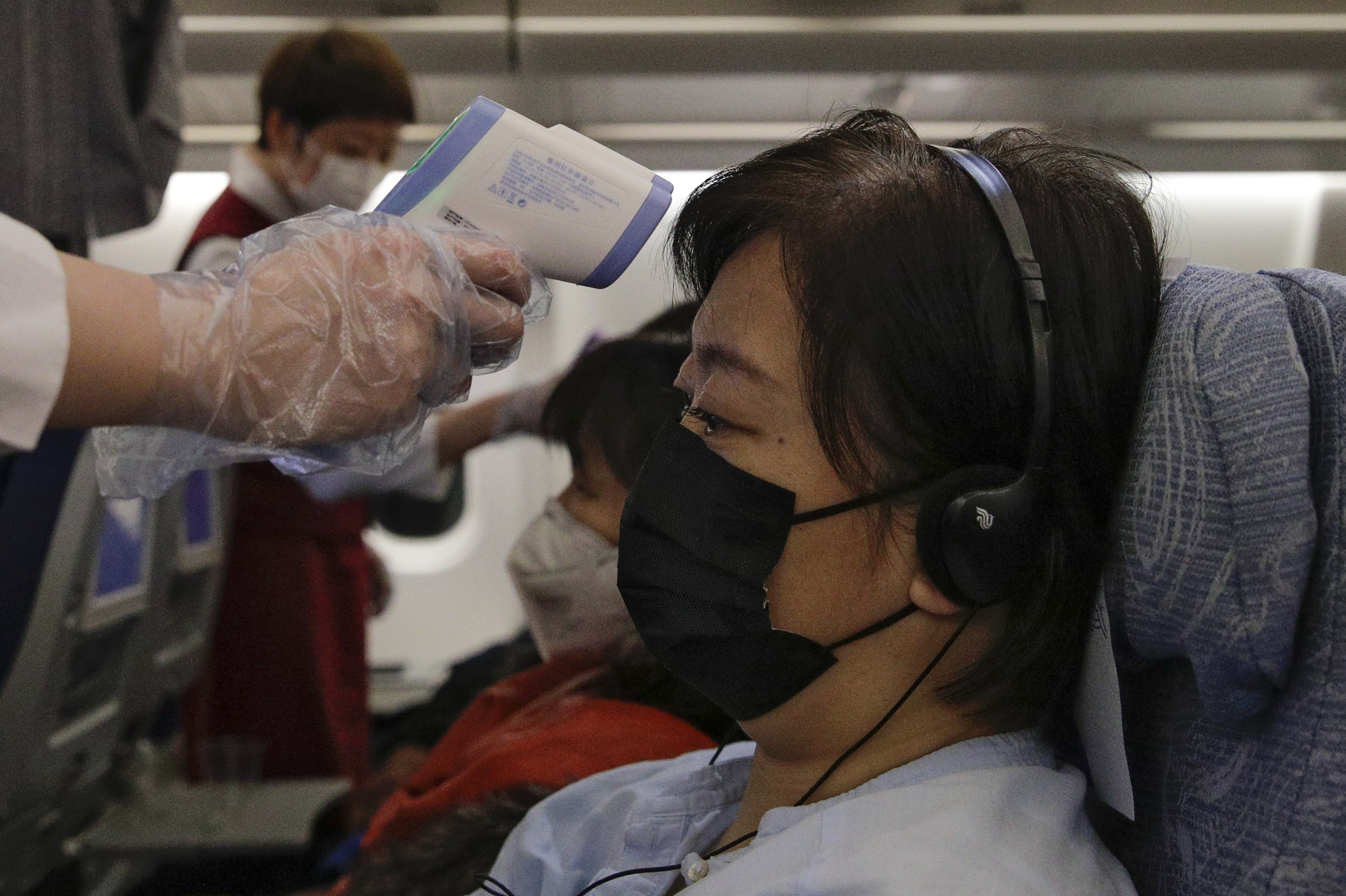 Flight attendants check temperatures of passengers aboard an Air China flight from Melbourne to Beijing on Feb. 4, 2020. AP Photo/Andy Wong