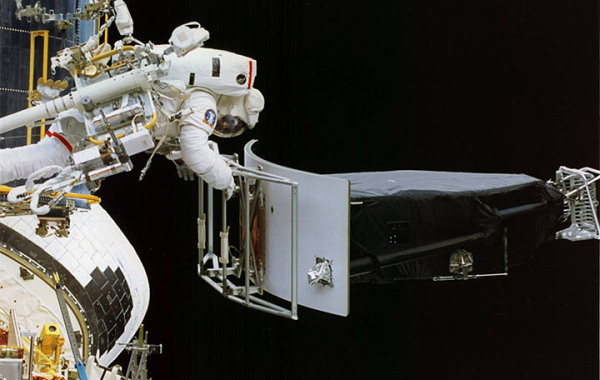 Image credit: NASA, of the first Hubble servicing mission. Astronaut Jeffrey Hoffman removes Wide Field and Planetary Camera 1 (WFPC 1) during change-out operations.