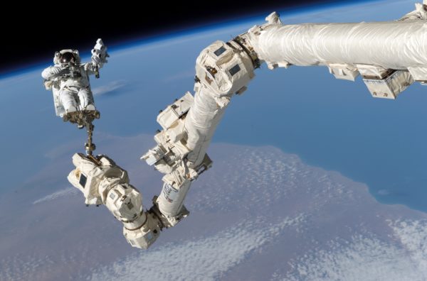 Astronaut Stephen K. Robinson, STS-114 mission specialist, anchored to a foot restraint on the International Space Station’s Canadarm2, participates in the mission’s third session of extravehicular activity (EVA). Image credit: NASA.