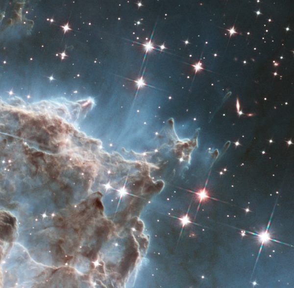 Infrared light penetrates more dust and gas than visible light, allowing details to become visible. A jet of material from a newly forming star is visible in one of the pillars, just above and left of center in the infrared image. Background galaxies are also visible. Image credit: NASA, ESA, and the Hubble Heritage Team (STScI/AURA), and J. Hester.