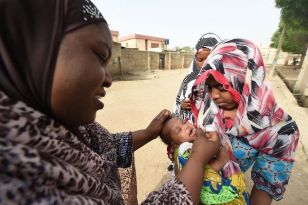 A Nigerian health worker tries to immunise a child during vaccination campaign against polio. The synchronised vaccination campaign, one of the largest of its kind ever implemented in Africa, is part of urgent measures to permanently stop polio on the continent. Image credit: PIUS UTOMI EKPEI/AFP/Getty Images.